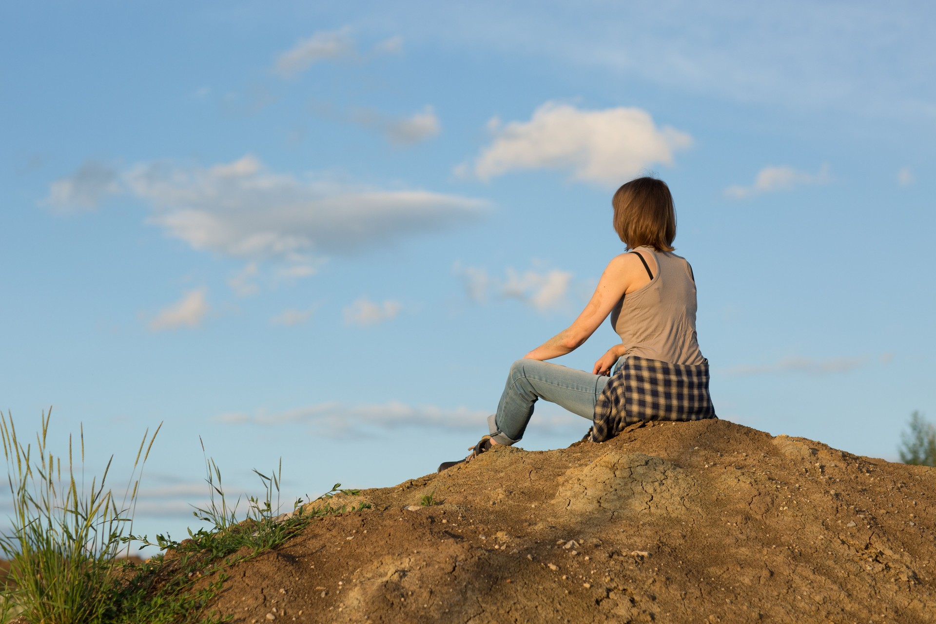 Woman construction worker sitting on the hill under blue sky